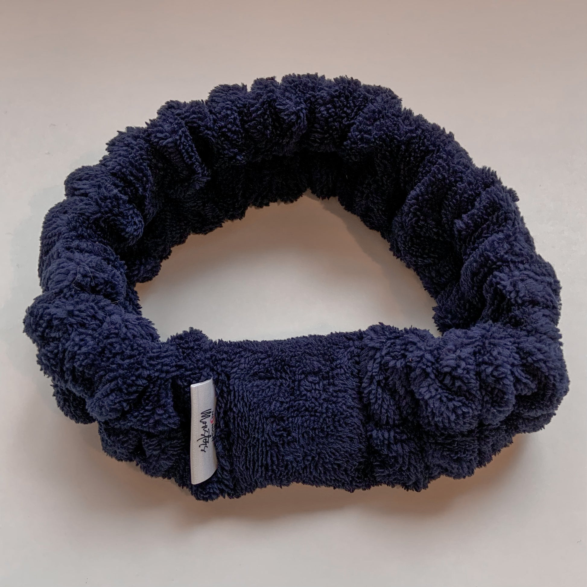 Bandeau de beauté en ratine de velours bleu foncé sur arrière-plan blanc.