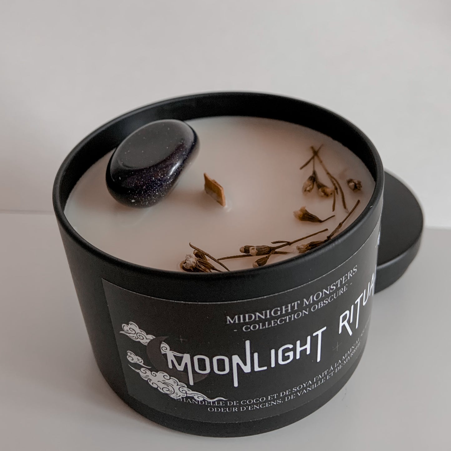 Chandelle Moonlight Ritual ouverte, focus sur la mèche de bois crépitante, les fleurs de Wax séchées et la pierre de Goldstone bleue, sur arrière-plan blanc.