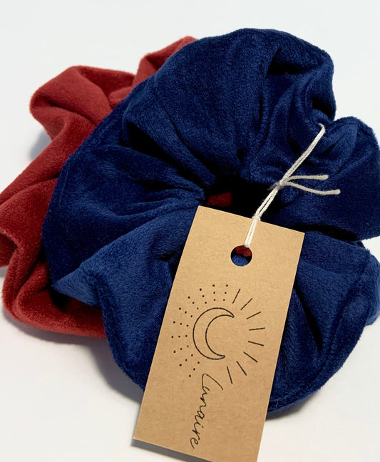 Duo d'élastique à cheveux Chouchou bleu velour et rouge velour sur arrière-plan blanc.