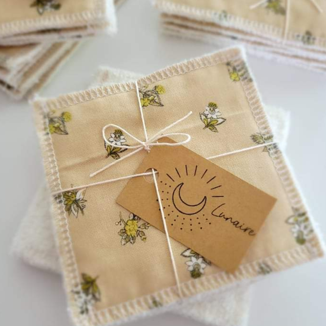 Paquets de trois tampons démaquillants de coton sur un arrière-plan blanc. Focus sur les fleurs dorées qui décorent le coton. 
